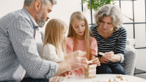 A family enjoying time together playing a block stacking game in their living room.