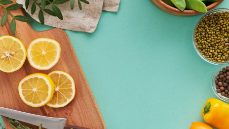 A bright flat lay of citrus fruits, vegetables, and spices on a teal background, perfect for culinary themes.