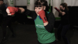 Energetic woman practicing boxing in a Buenos Aires gym with classmates.
